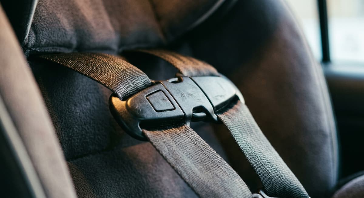 Un broche de pecho abrochado a través del arnés de un asiento de auto, primer plano ajustado