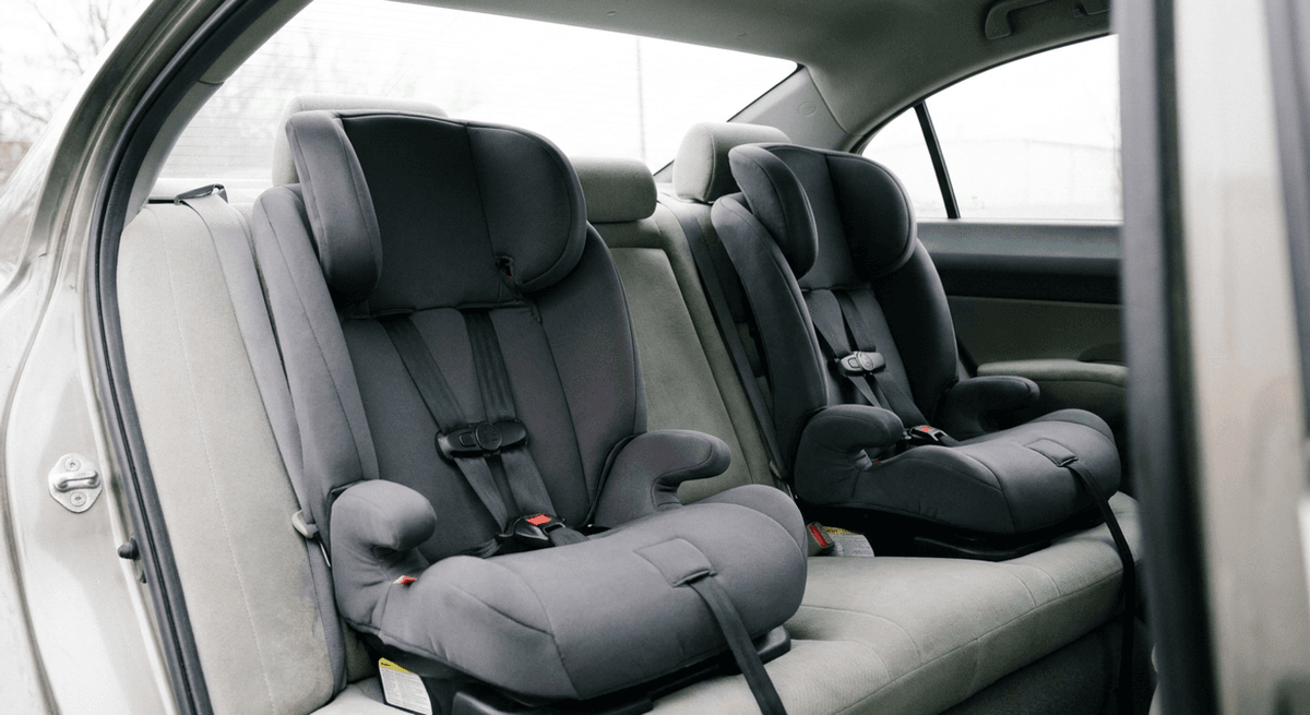 two plain grey child car seats installed side by side on a car back seat