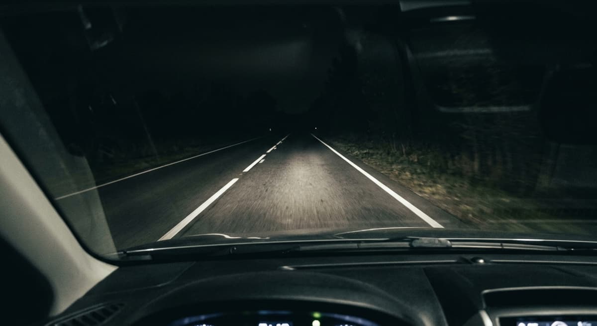 Vista de vision nocturna de camara de tablero de una carretera oscura con faros que iluminan las marcas del carril en Virginia Occidental
