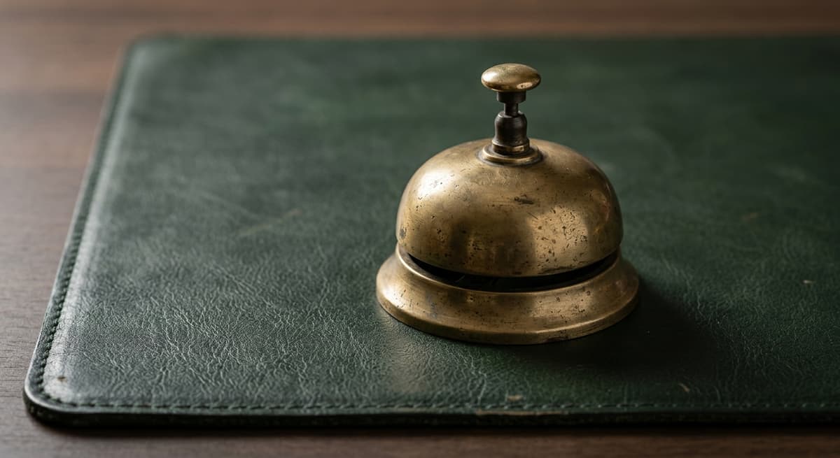 Alabama vintage brass desk bell on a dark green leather desk mat